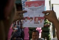 Ilustrasi seorang memperlihatkan kertas surat suara di TPS, foto dari laman https://nasional.tempo.co/