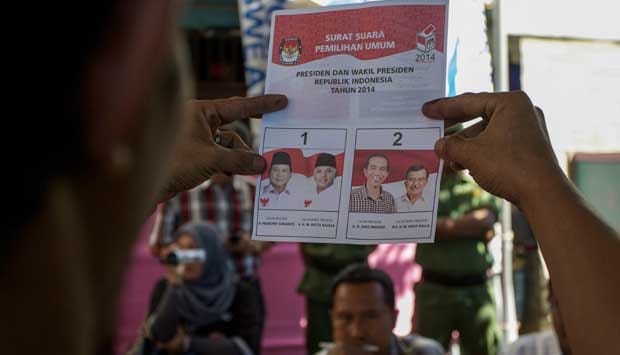 Ilustrasi seorang memperlihatkan kertas surat suara di TPS, foto dari laman https://nasional.tempo.co/