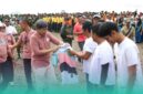 Bupati Jember, Muhammad Fawait membagikan kaos saat acara aksi bersih-bersih pantai di kawasan Pantai Selatan Jember. (Foto: Istimewa). 