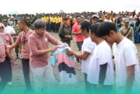 Bupati Jember, Muhammad Fawait membagikan kaos saat acara aksi bersih-bersih pantai di kawasan Pantai Selatan Jember. (Foto: Istimewa). 