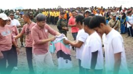 Bupati Jember, Muhammad Fawait membagikan kaos saat acara aksi bersih-bersih pantai di kawasan Pantai Selatan Jember. (Foto: Istimewa). 