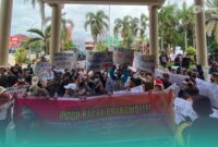 Massa aksi saat membentangkan poster dukungan pada Program MBG di depan Gedung DPRD Jember (Foto: Sigit/Frensia). 