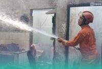 Petugas pemadam kebakaran (Damkar) Jember, saat memadamkan api di sela-sela keramik rumah yang terbakar. (Foto: Istimewa). 