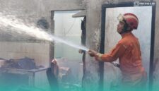 Petugas pemadam kebakaran (Damkar) Jember, saat memadamkan api di sela-sela keramik rumah yang terbakar. (Foto: Istimewa).